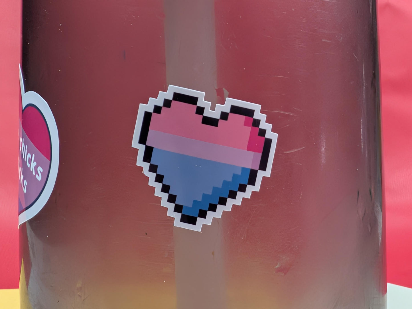 Pixelated bi pride heart sticker on a red background