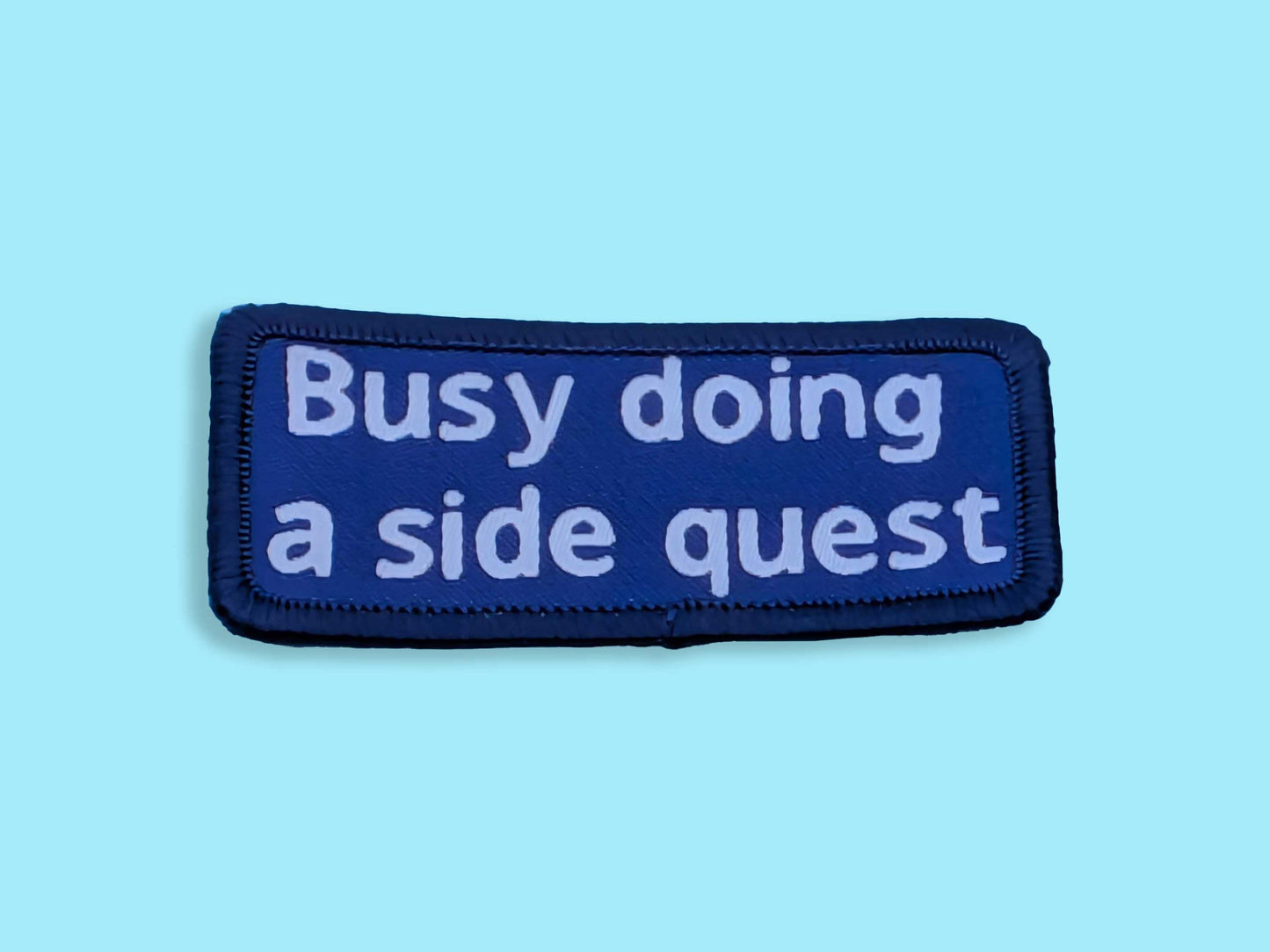 Blue patch with white text 'Busy doing a side quest' on a light blue background