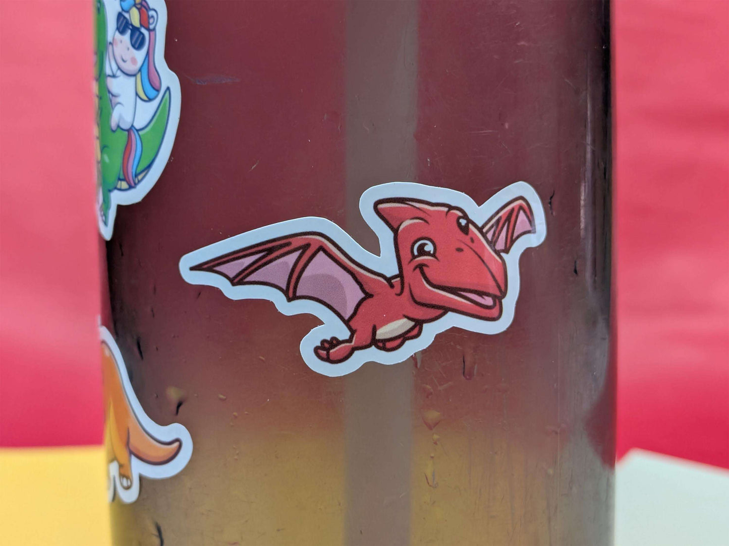 Red dinosaur sticker on a colourful background
