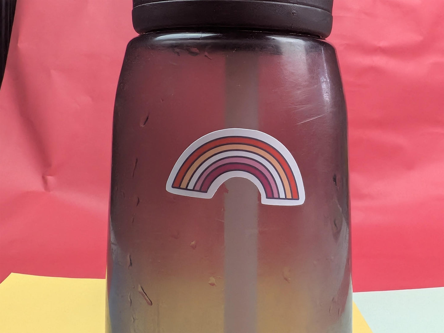 Gradient water bottle with rainbow sticker on a red background