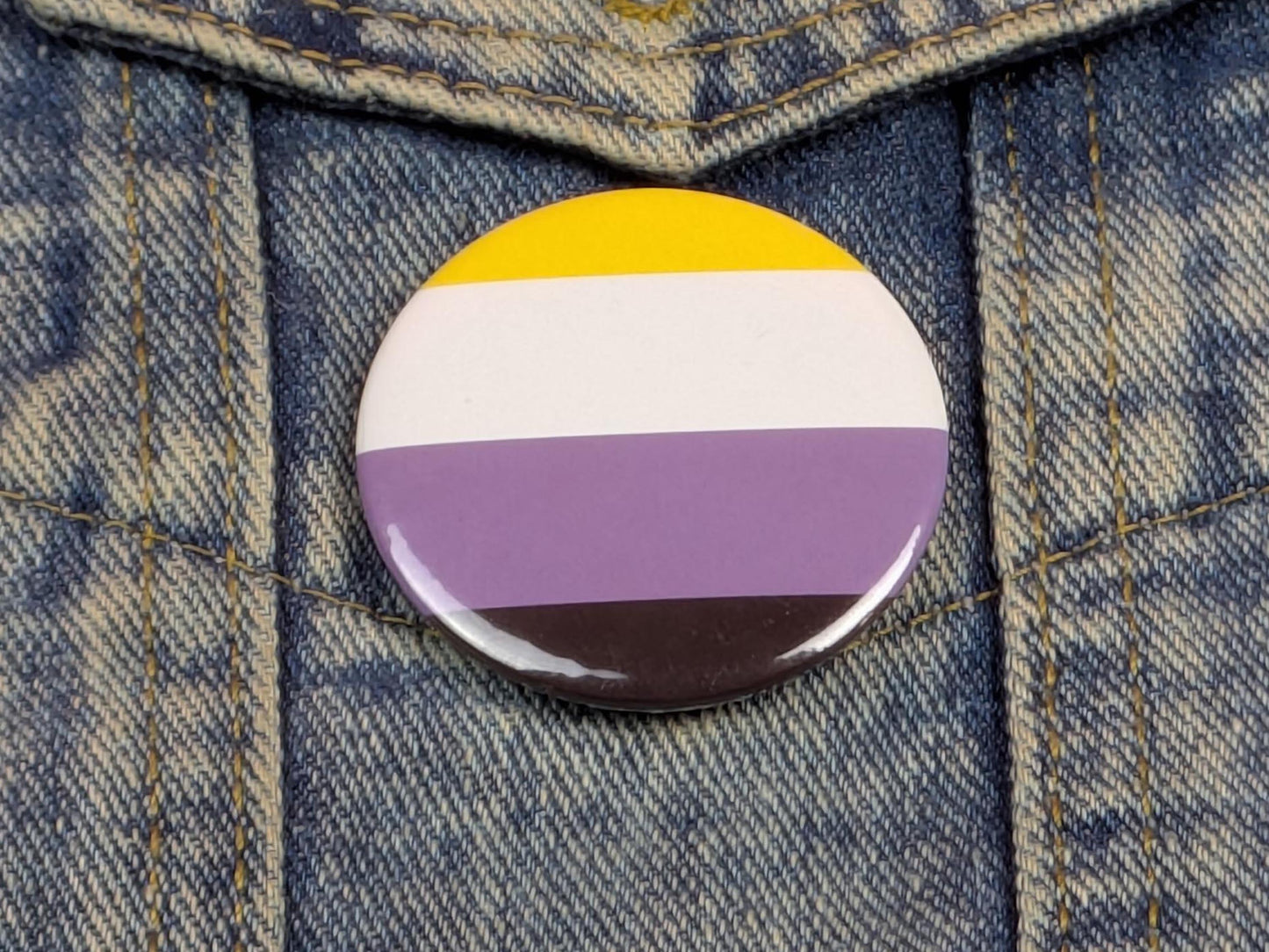 Button with a non-binary pride flag on a denim background