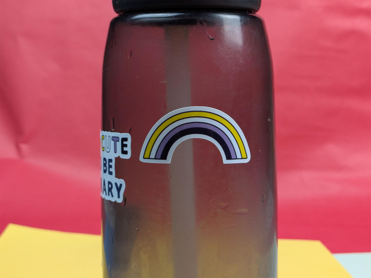 Bottle with a rainbow sticker and text on a red and yellow background