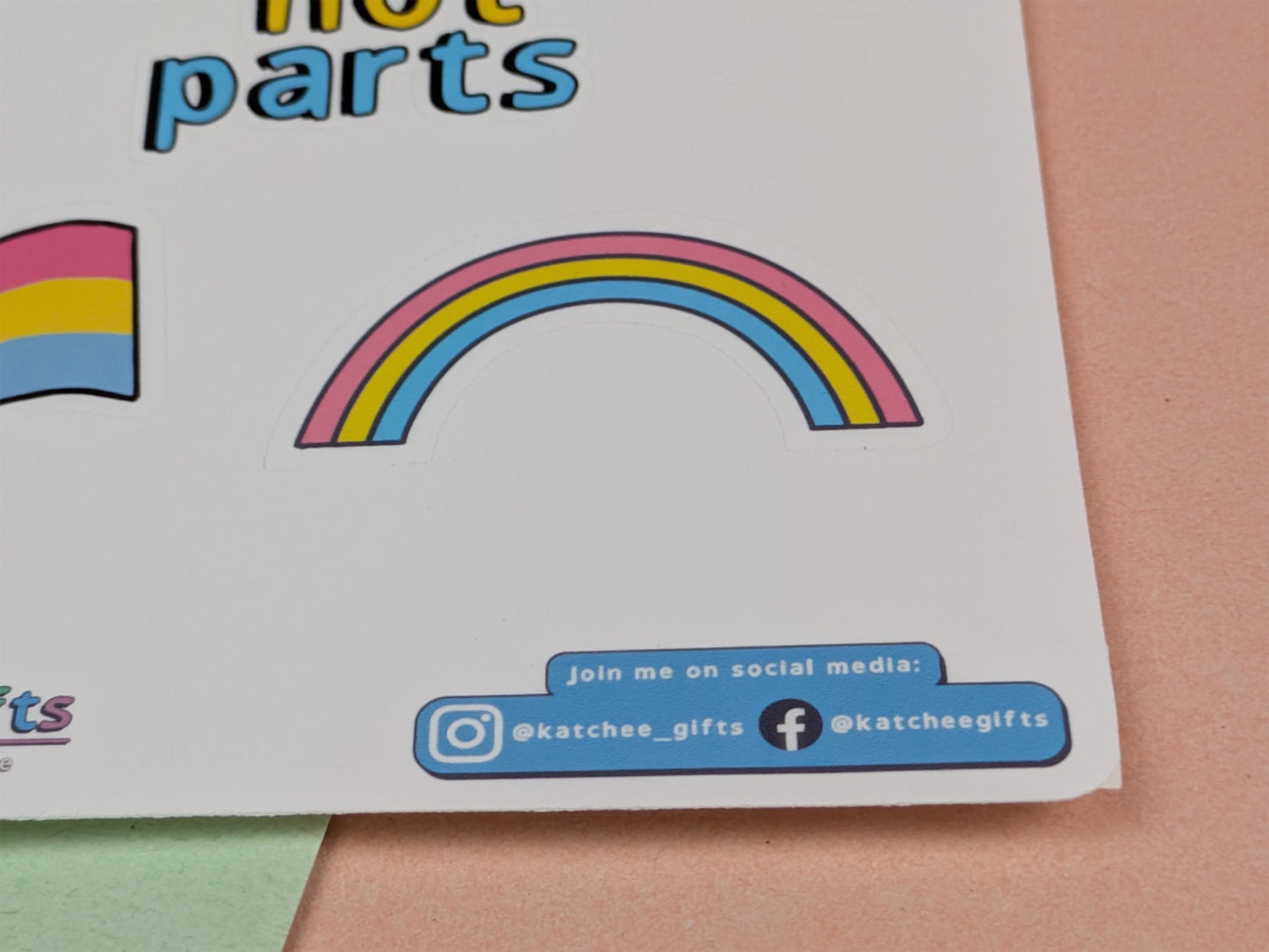 Sticker with a rainbow design and social media information on a pink background