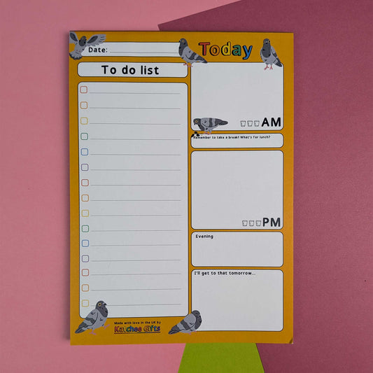 A daily to-do list notepad with pigeon illustrations, featuring a yellow border and white writing sections, photographed flat on a pink background with a green shape peeking from behind.