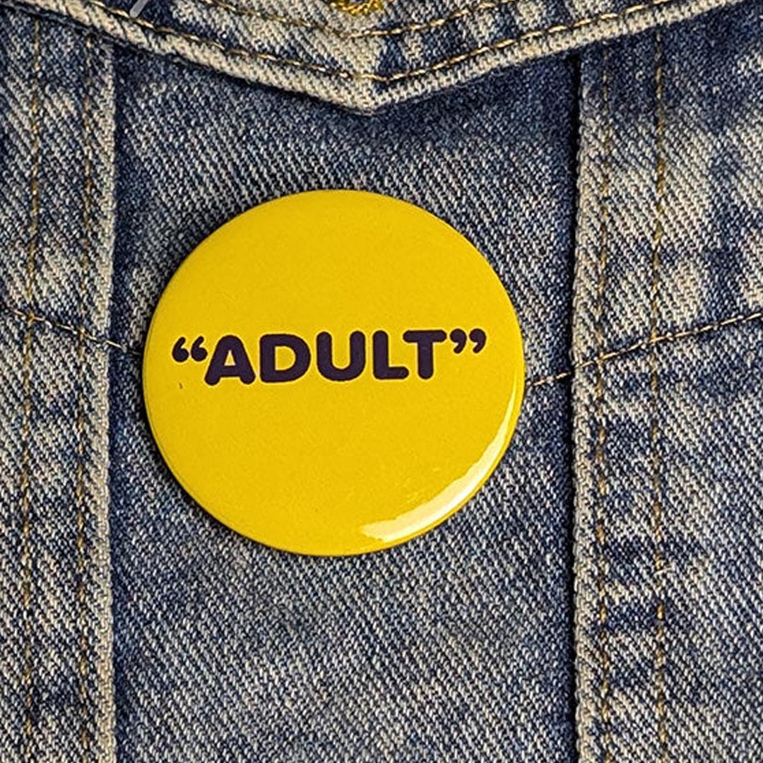 Yellow button with 'ADULT' text on a denim jacket