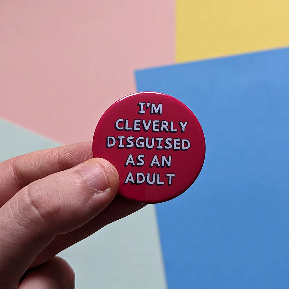 Hand holding a dark pink button with text against a colourful background