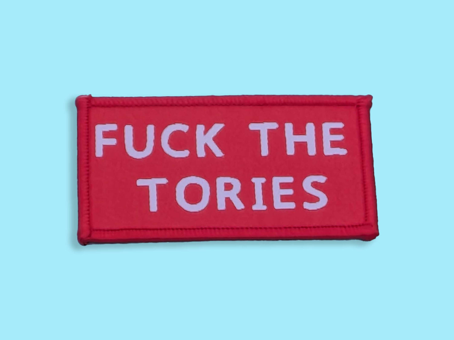 Red patch with white text 'FUCK THE TORIES' on a light blue background
