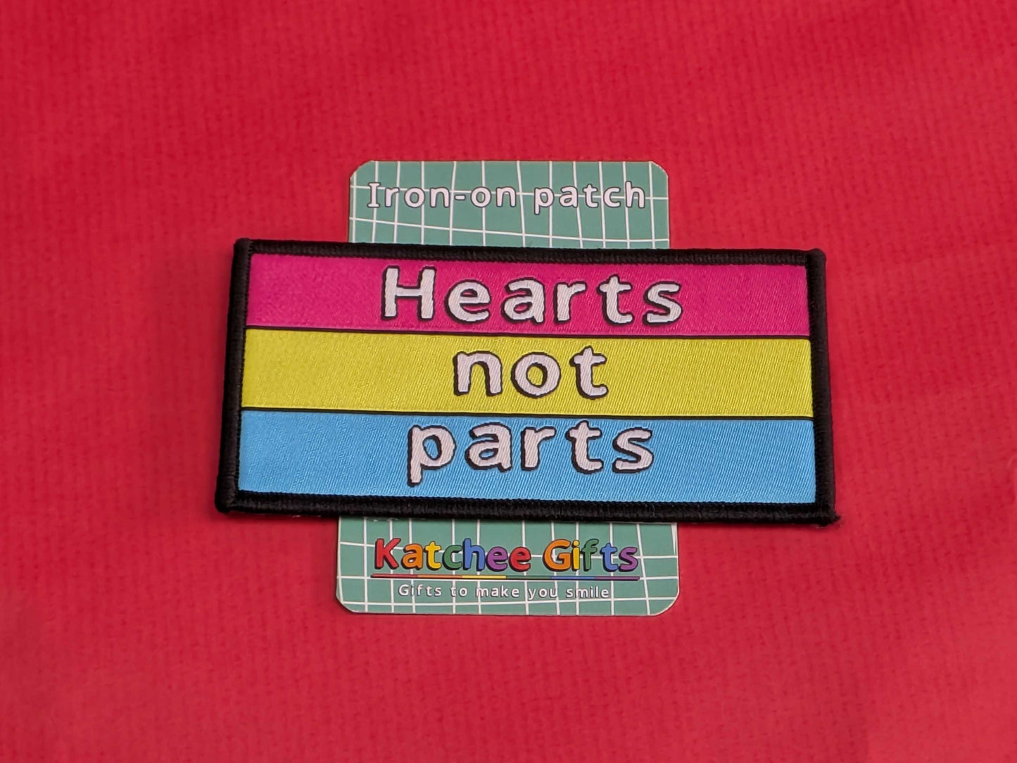 Iron-on patch with 'Hearts not parts' text on a red background, branded as Katchee Gifts.