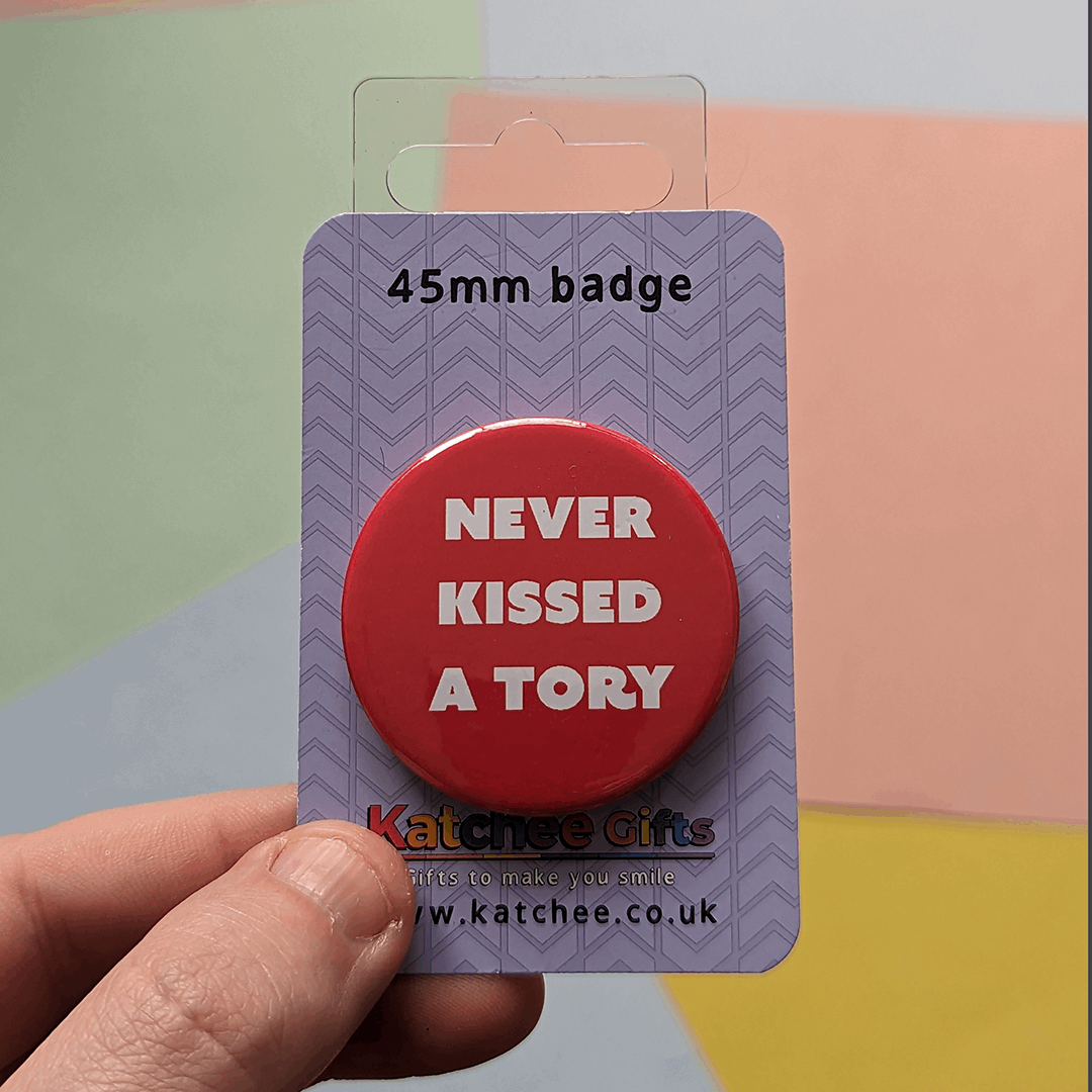 A circle pin badge with the words "never kissed a tory" on Katchee gifts branded backing card, on a colourful background
