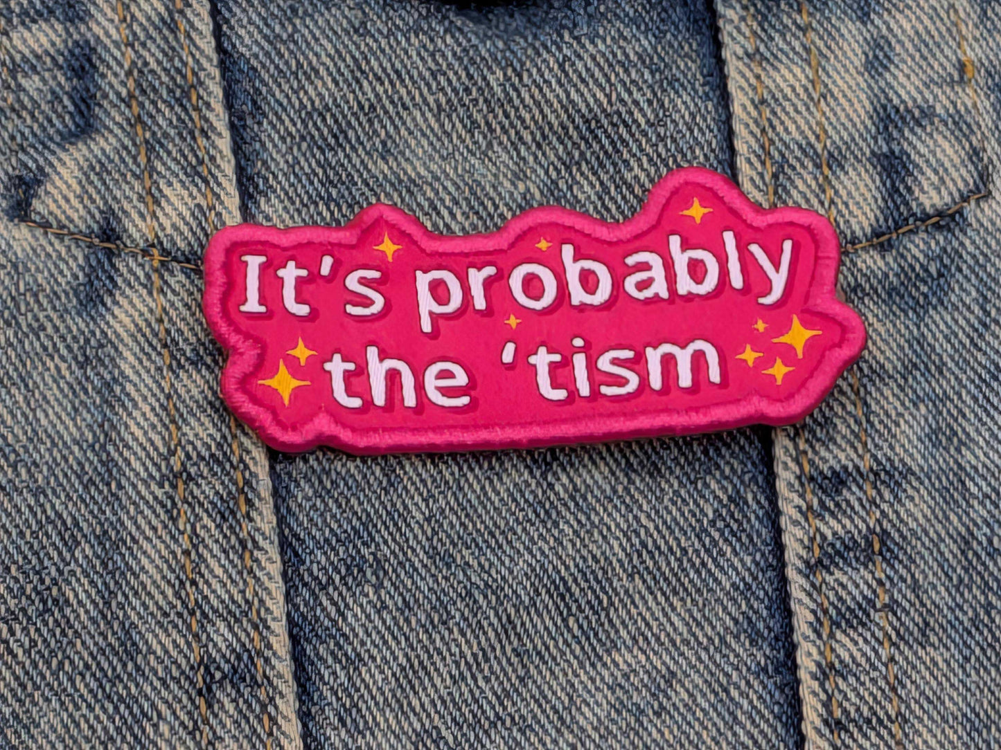 Pink patch with text 'It's probably the 'tism' on a denim background