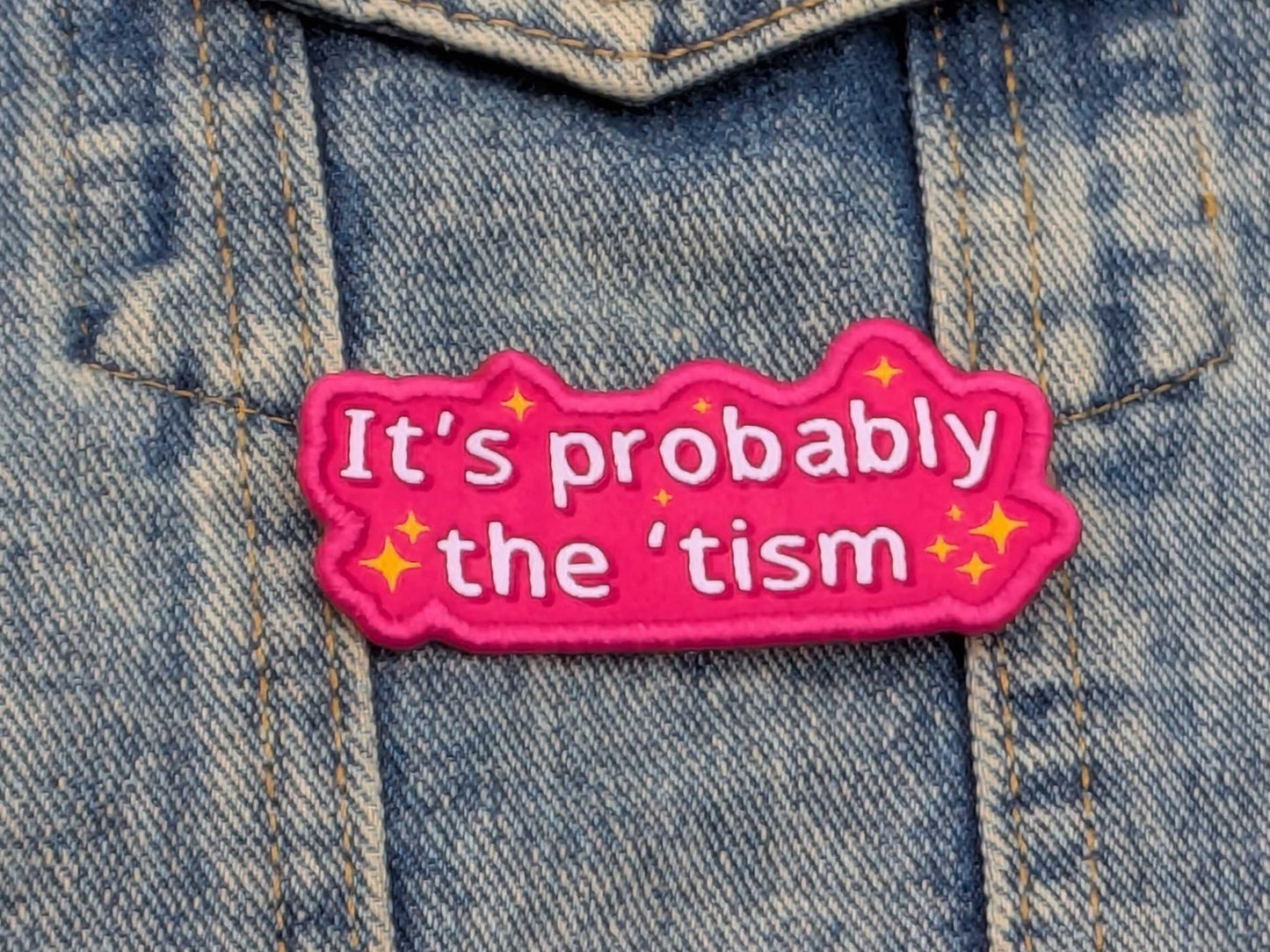 Pink patch with text 'It's probably the 'tism' on a denim background