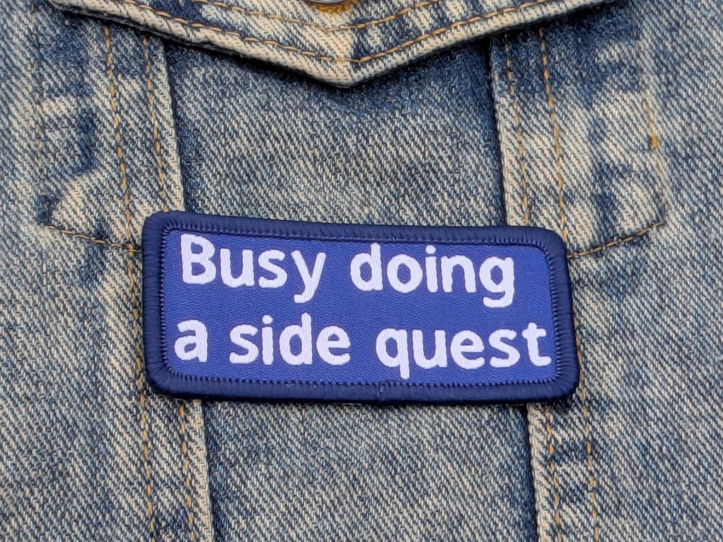 Patch on denim fabric with text 'Busy doing a side quest'