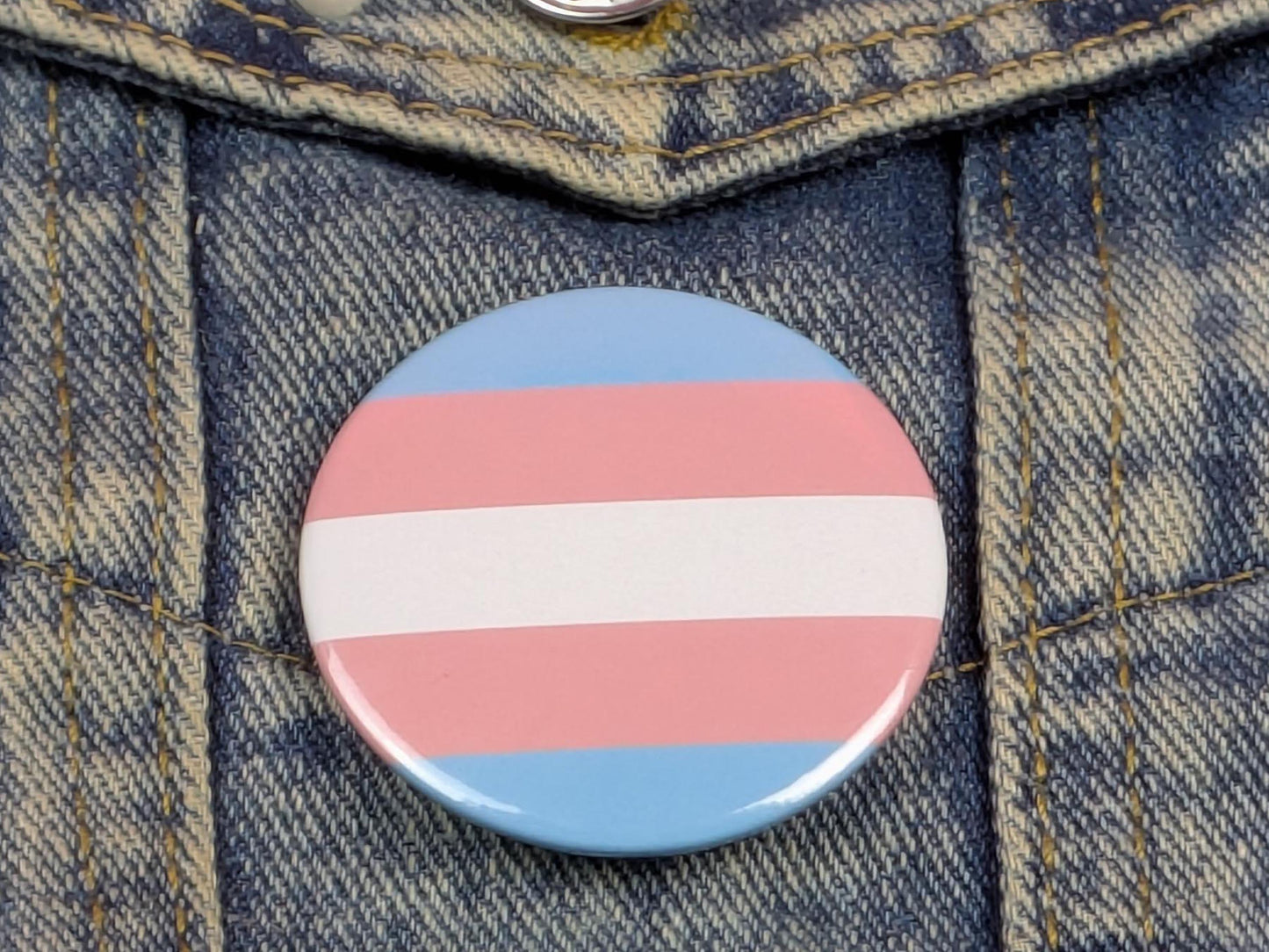Trans flag pin badge on denim background