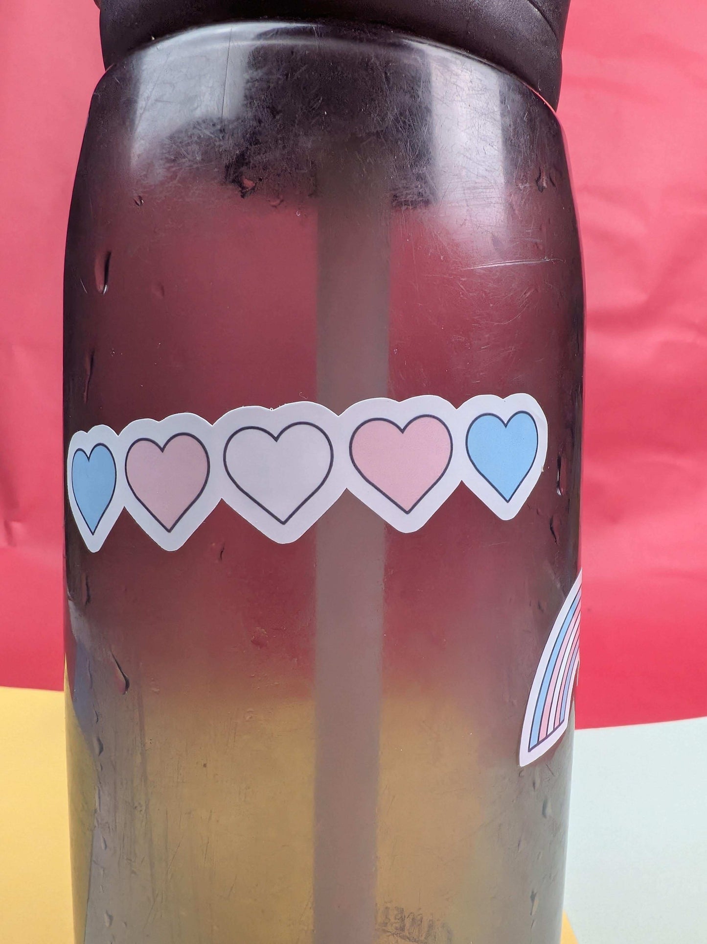 Gradient bottle with heart-shaped stickers on a red and yellow background