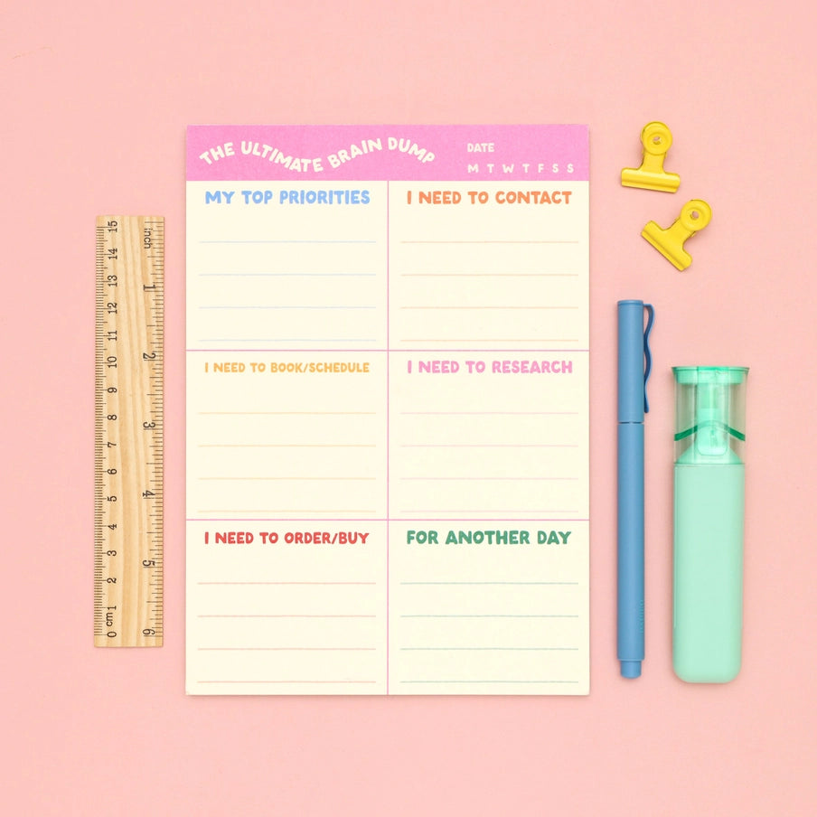 Notebook with a planner layout on a pink background with stationery items.
