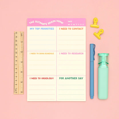 Notebook with a planner layout on a pink background with stationery items.
