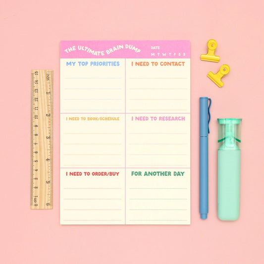 Notebook with a planner layout on a pink background with stationery items.