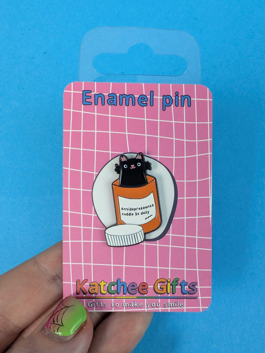 Enamel pin on a pink card with 'Katchee Gifts' branding against a blue background