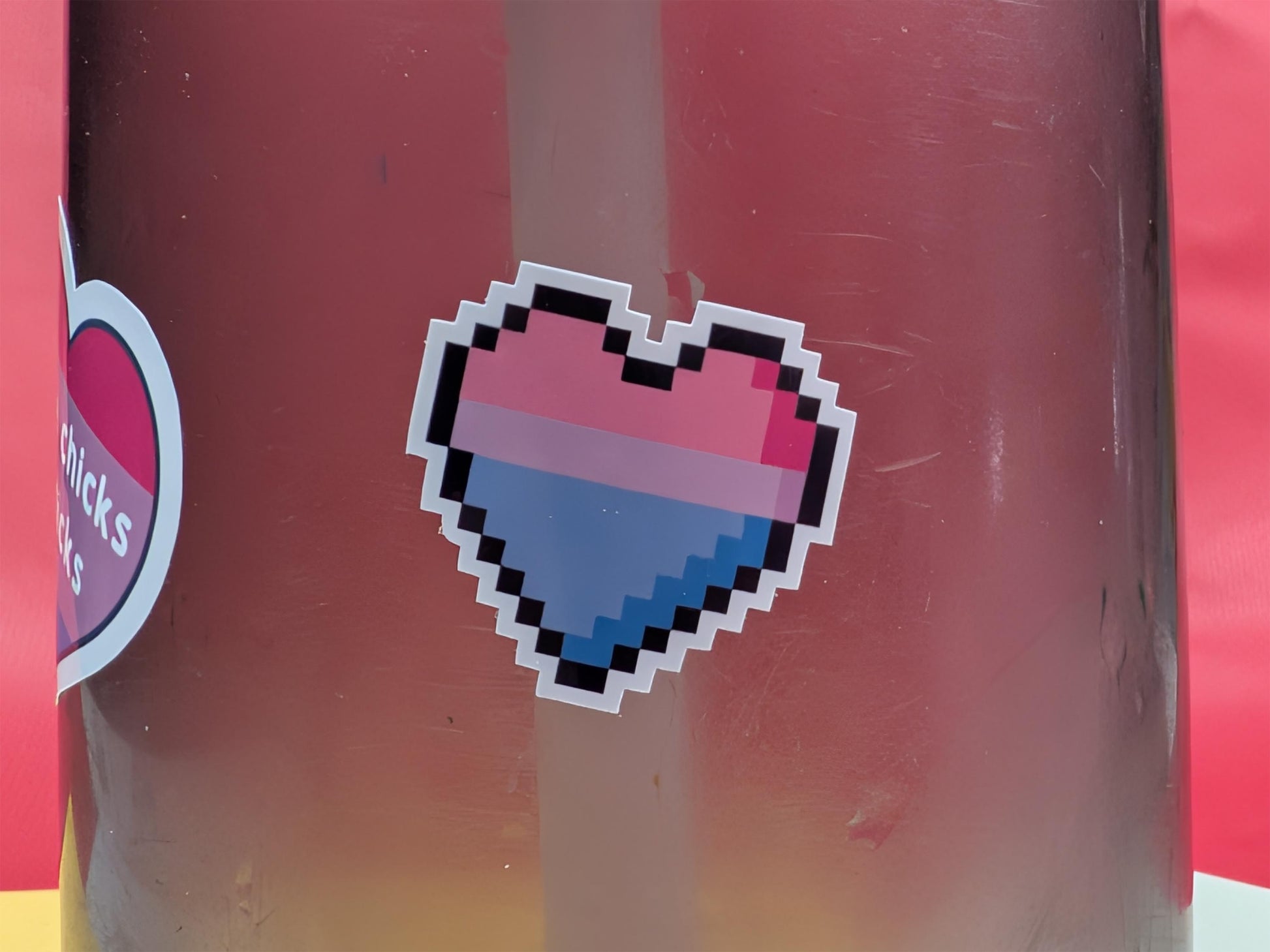 Pixelated bi pride heart sticker on a red background