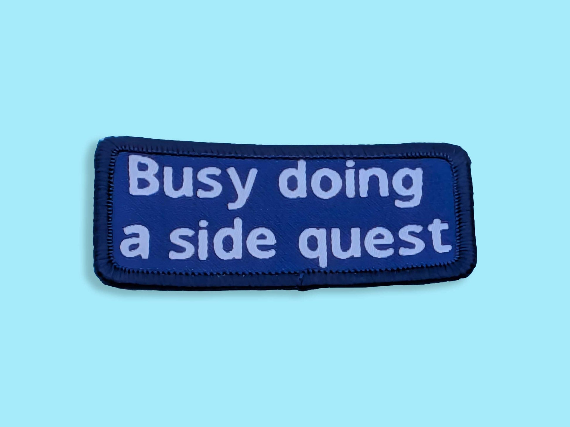 Blue patch with white text 'Busy doing a side quest' on a light blue background