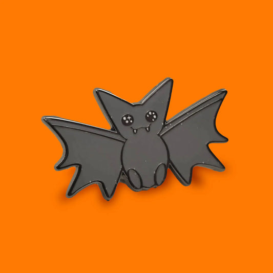 Black bat-shaped pin on an orange background