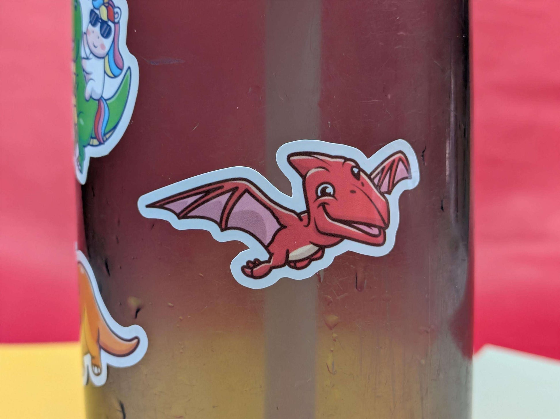 Red dinosaur sticker on a colourful background