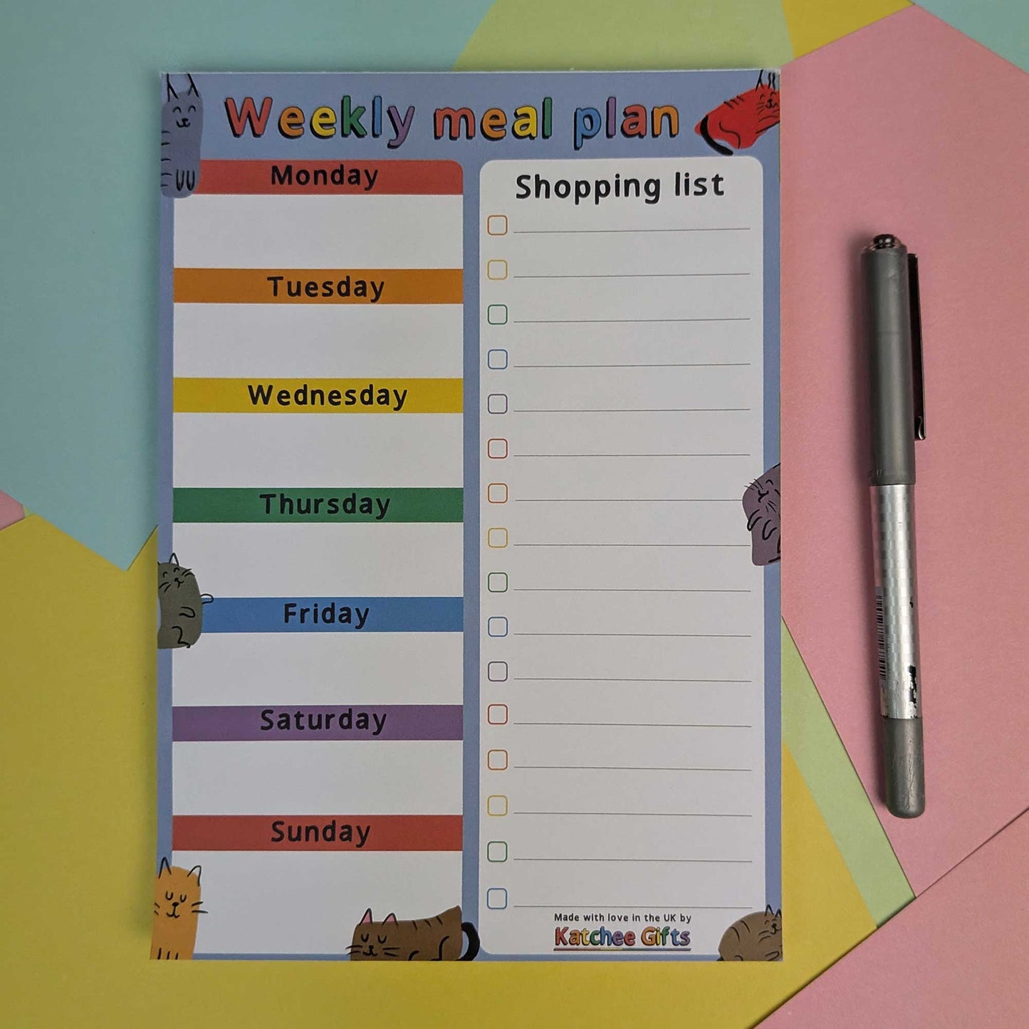 Weekly meal plan and shopping list notepad with a pen on a colourful background