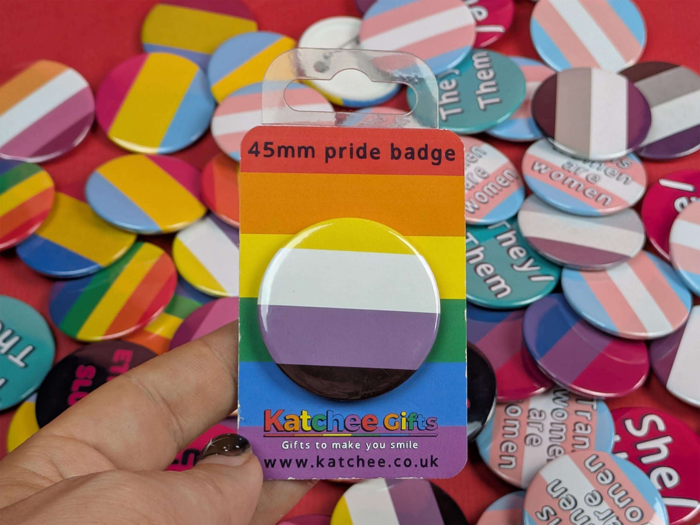 Non binary flag badge on a colourful background with 'Katchee Gifts' packaging
