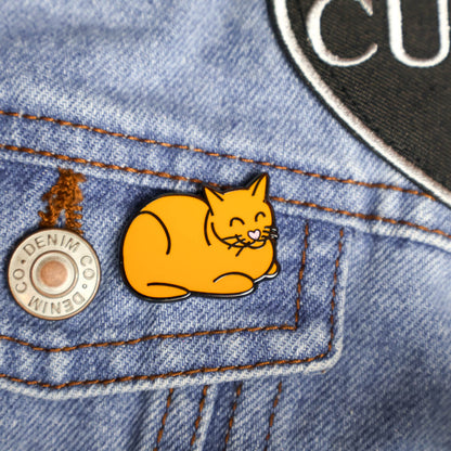Orange cat enamel pin on a denim background