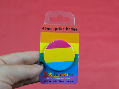 pansexual flag badge in packaging held by a hand against a red background