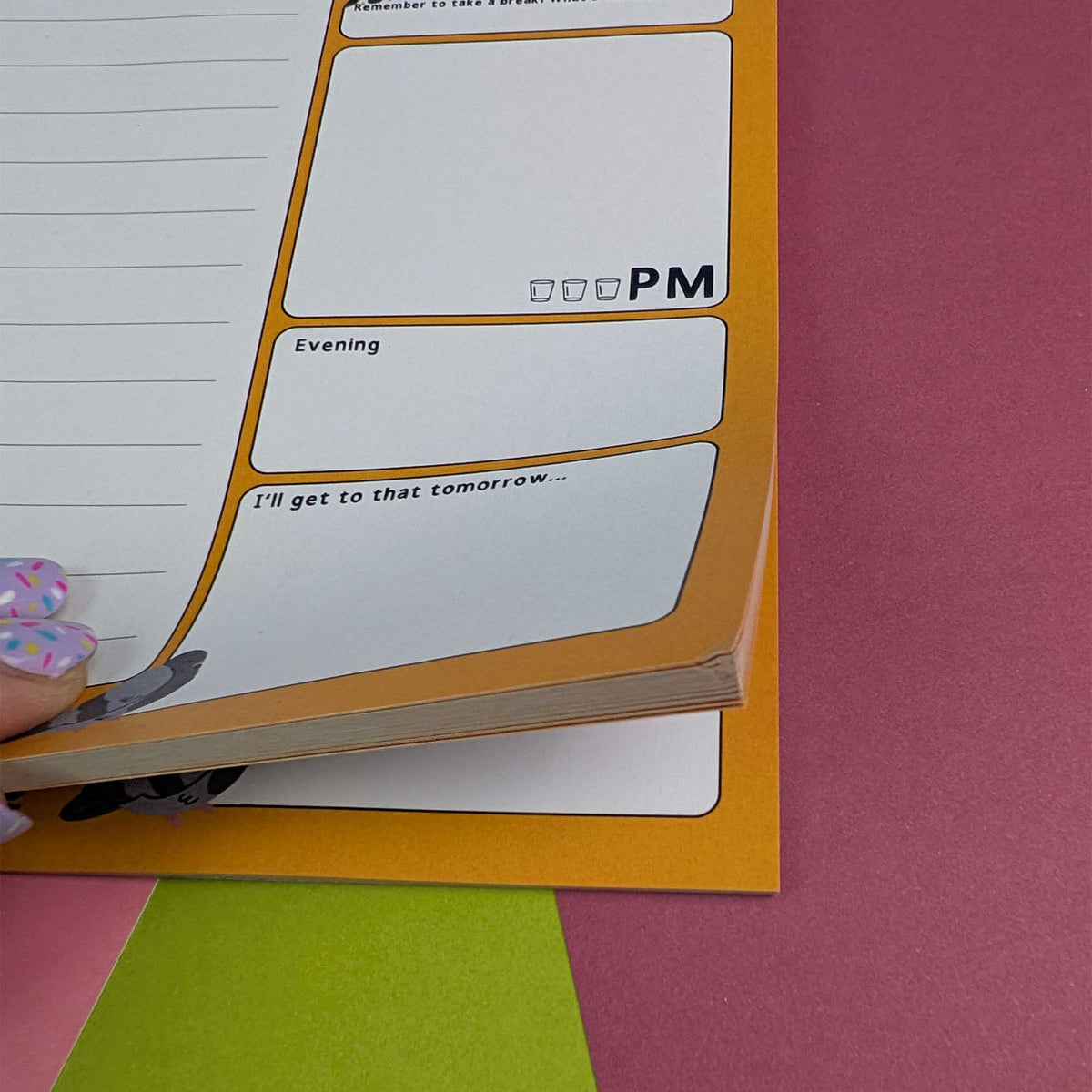 A close-up of a planner notepad page being held by a hand with pastel nail art. The page has lined writing space, labeled sections for PM, Evening, and a note saying 'I'll get to that tomorrow.