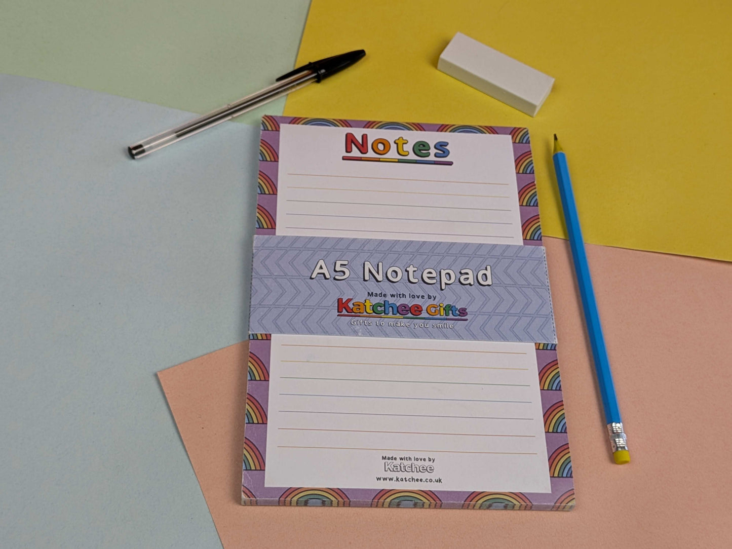 A5 notepad with colourful design on a multicoloured background with stationery items.