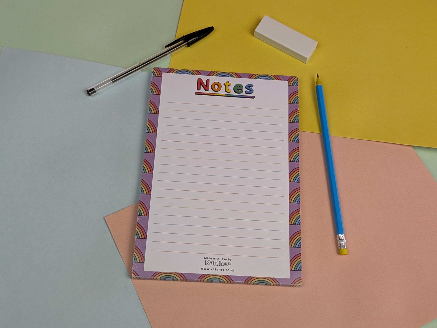 Notepad with colorful border, pen, pencil, and eraser on a multicolored background