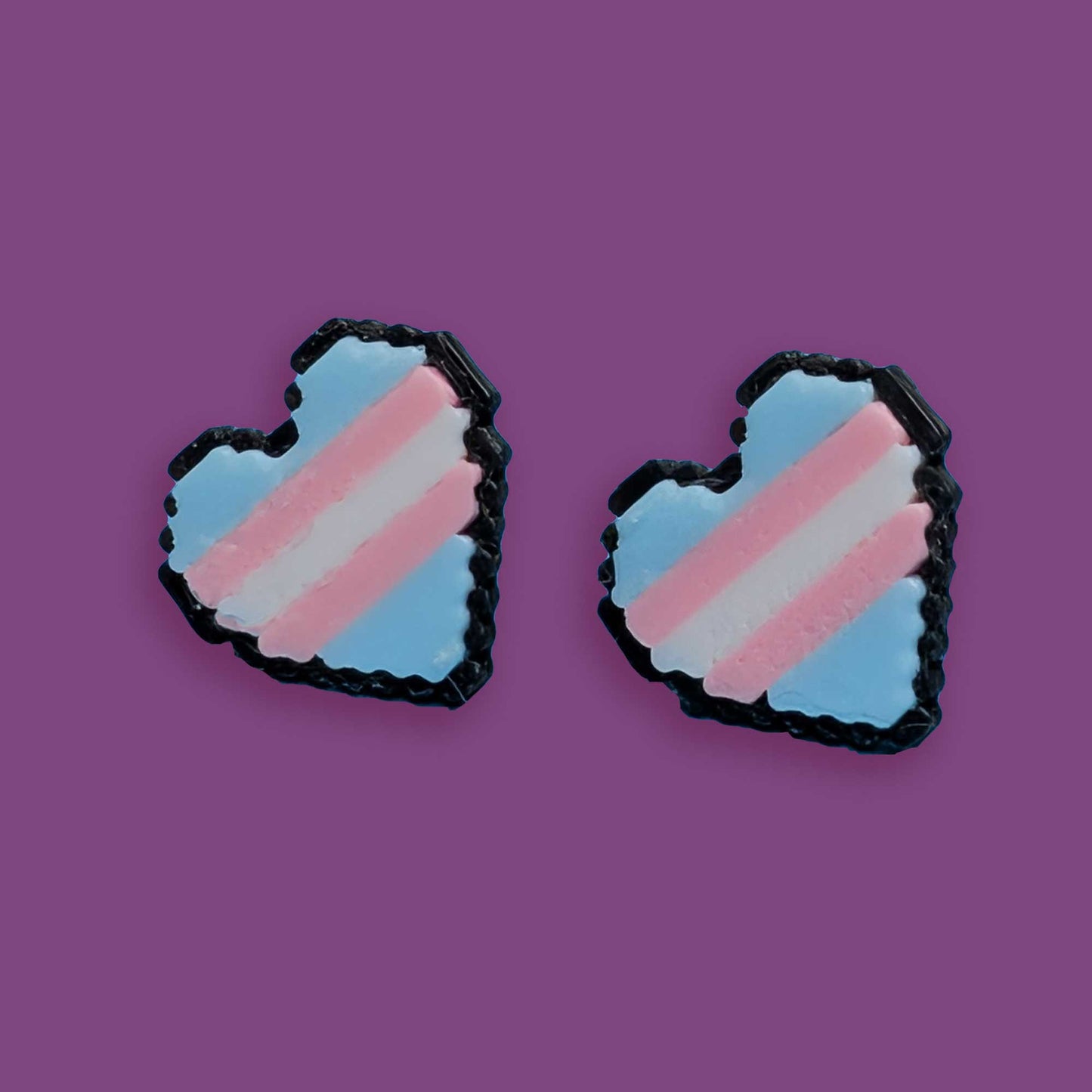 Heart-shaped earrings with a transgender flag design on a purple background