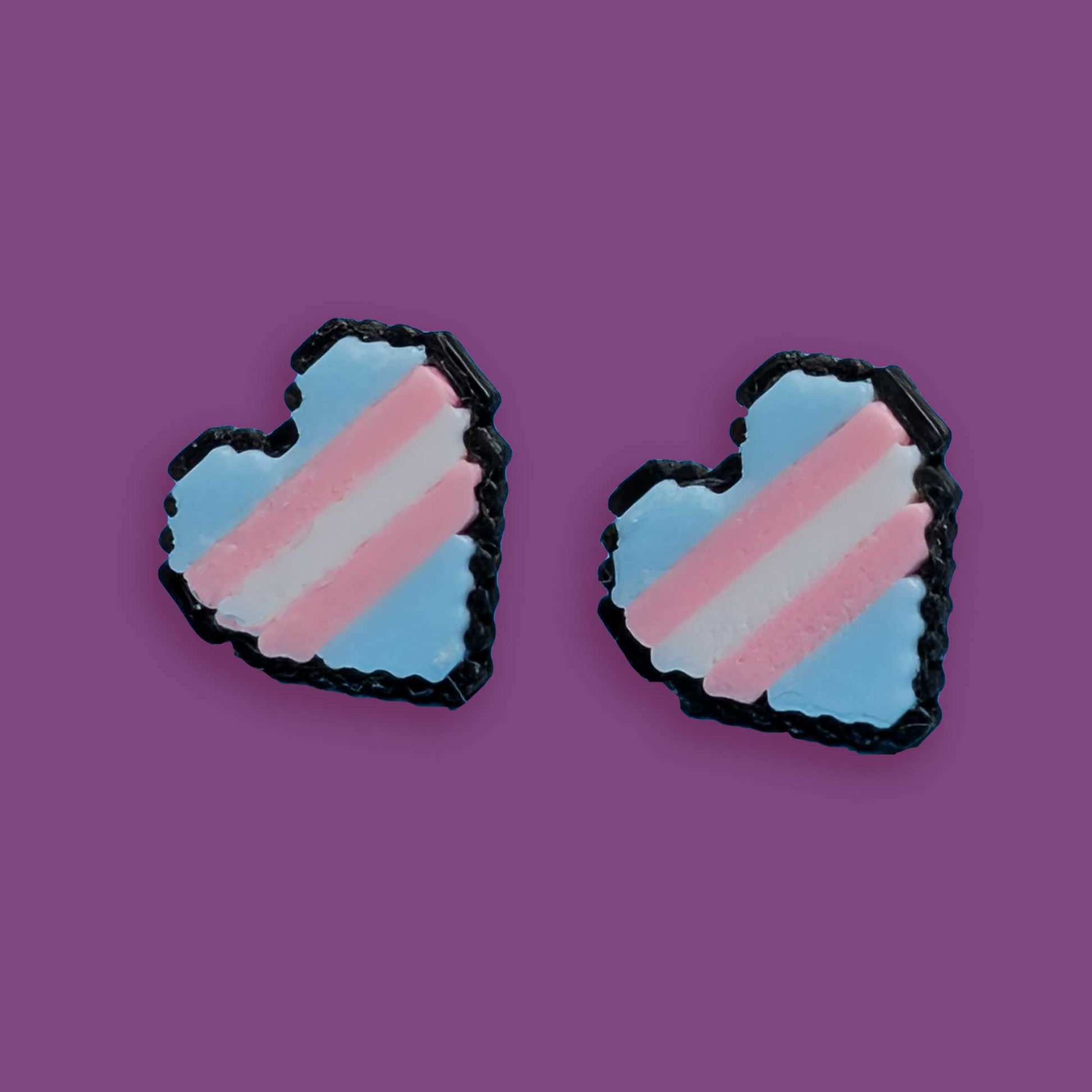Heart-shaped earrings with a transgender flag design on a purple background