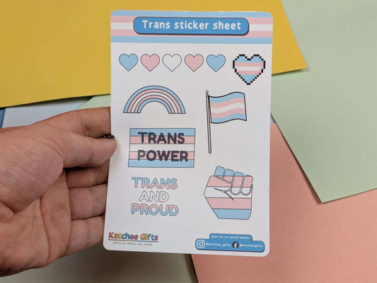 Trans sticker sheet with symbols and text held by a hand against a colorful background