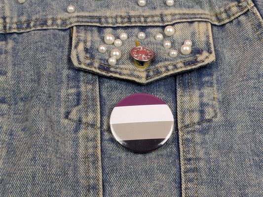 Denim jacket with a button featuring an asexual pride flag.