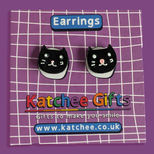Black cat-shaped earrings on a purple grid background with 'Katchee Gifts' branding.