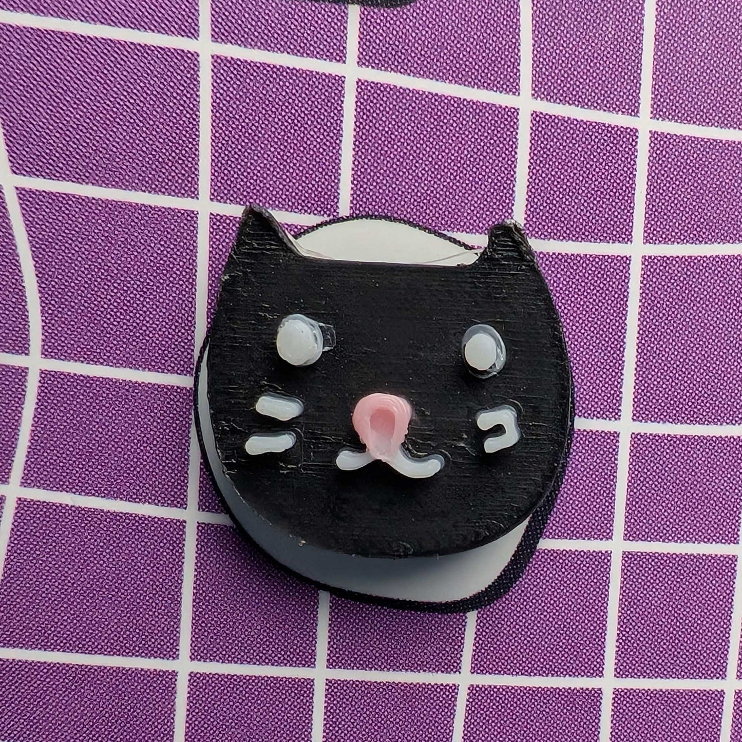 Black cat-shaped object on a purple grid background