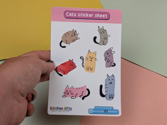 Sheet of cat stickers held by a hand against a colourful background