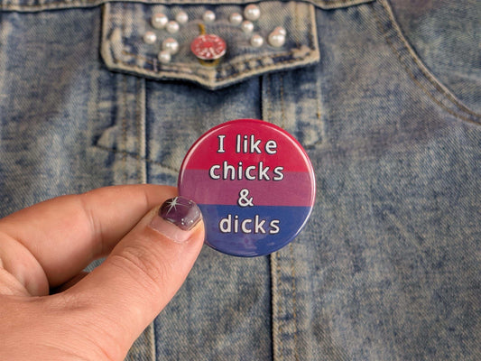Button with text 'I like chicks & dicks' held by a hand against a denim background