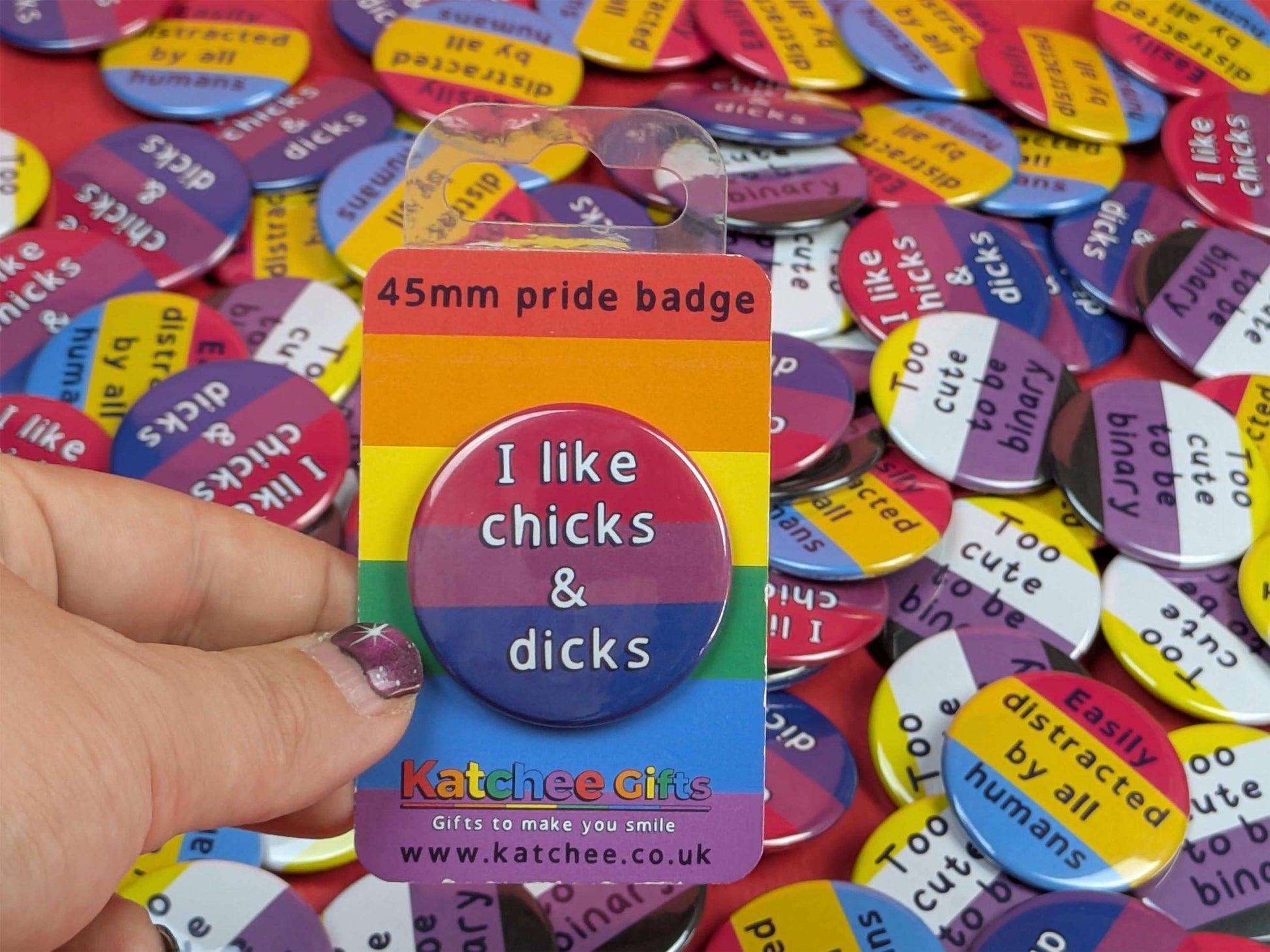 Packaged pin badge that says " I like chicks and dicks" on a background of other pin badges