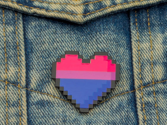 Pixelated heart-shaped pin with bisexual flag colors on a denim background
