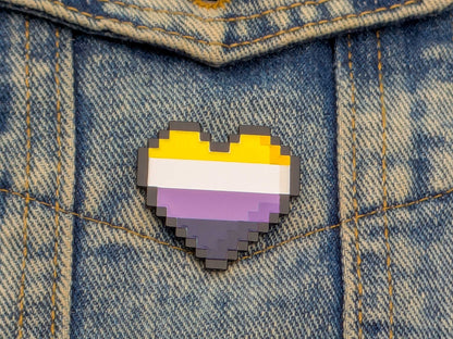 Pixelated heart-shaped pin with a non binary flag design on denim fabric