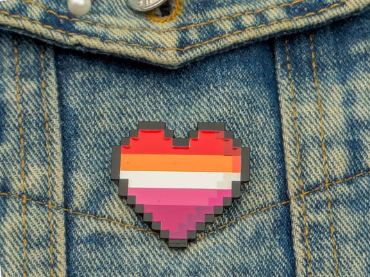 Lesbian flag coloured heart shaped enamel pin on a denim background