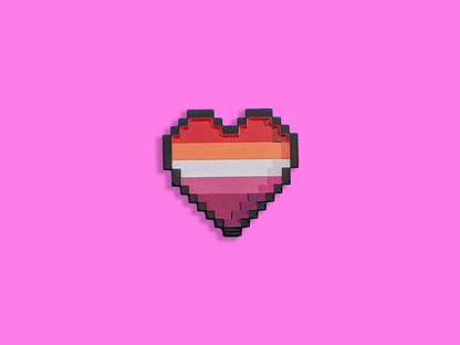 Lesbian flag coloured heart shaped enamel pin on a pink background