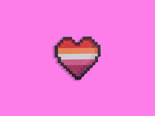 Lesbian flag coloured heart shaped enamel pin on a pink background