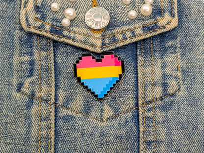 Pixelated heart-shaped pin with pansexual flag colors on a denim jacket.