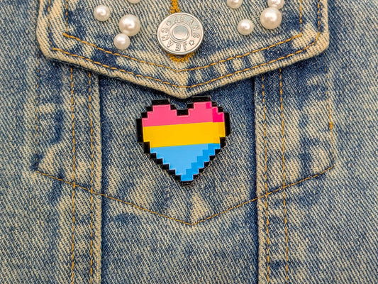 Pixelated heart-shaped pin with pansexual flag colors on a denim jacket.