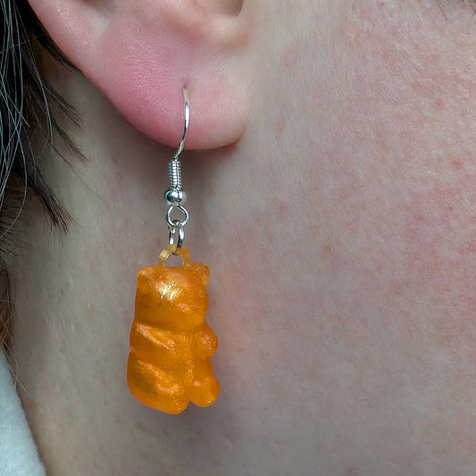 Orange gummy bear-shaped earring on a person's ear